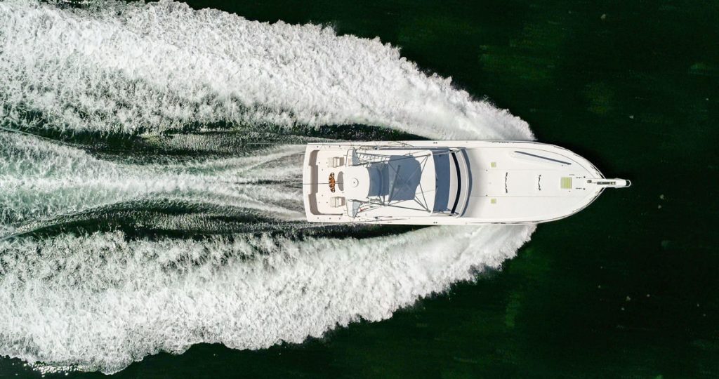 Top-down aerial view of a white luxury yacht cruising on the water.