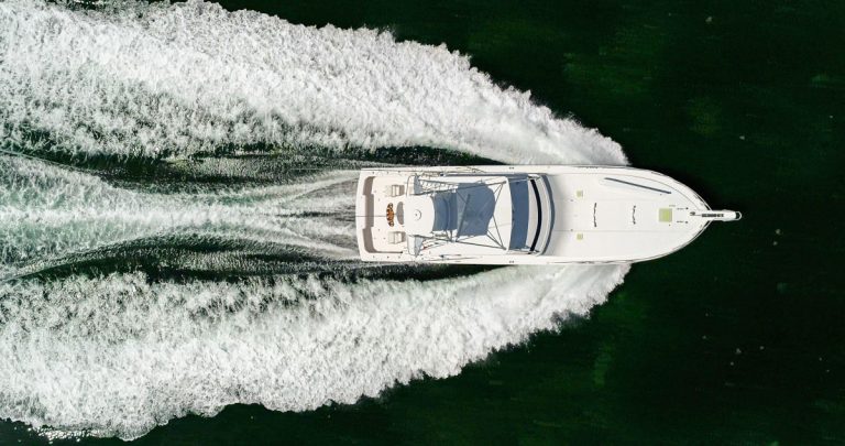 Top-down aerial view of a white luxury yacht cruising on the water.