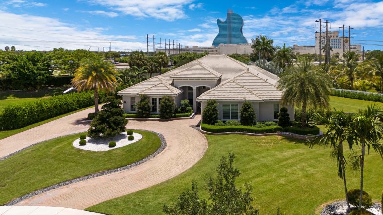 Luxury South Florida home with landscaped grounds and palm trees.