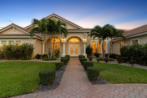 Elegant Florida home with tropical palm trees and manicured lawn at sunset.