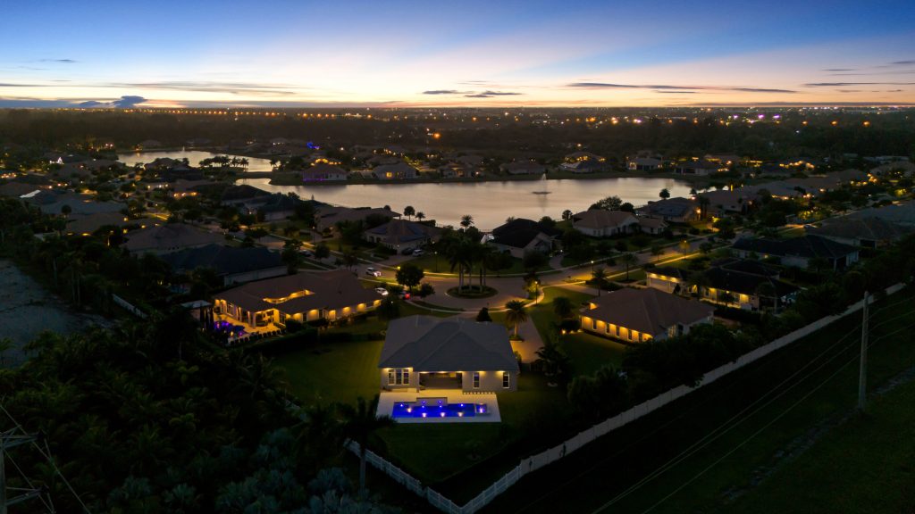 Luxury lakeside homes at sunset in a gated community, showcasing scenic views and modern architectur.