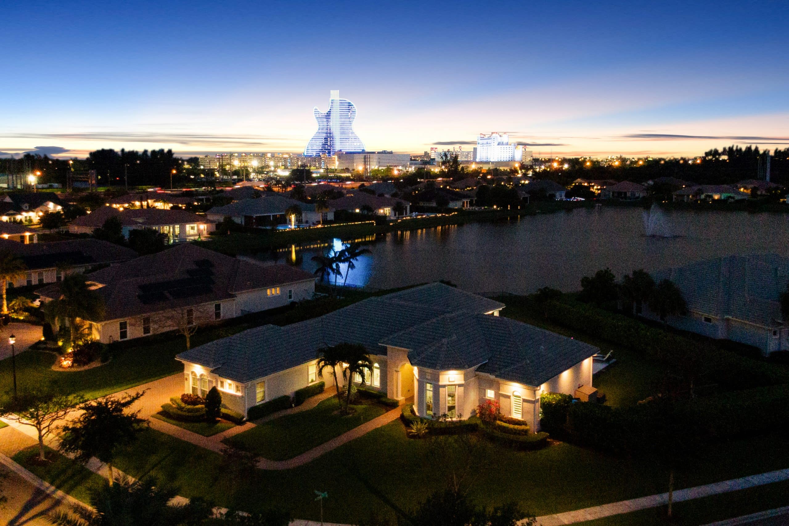 Beautiful waterfront homes illuminated at dusk with city skyline and unique architectural buildings.