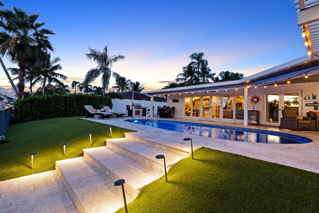 Outdoor pool and lounge area with tropical palm trees at dusk.