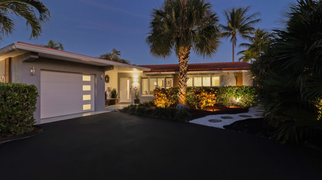 Modern tropical house with palm trees and sunset sky in the background.
