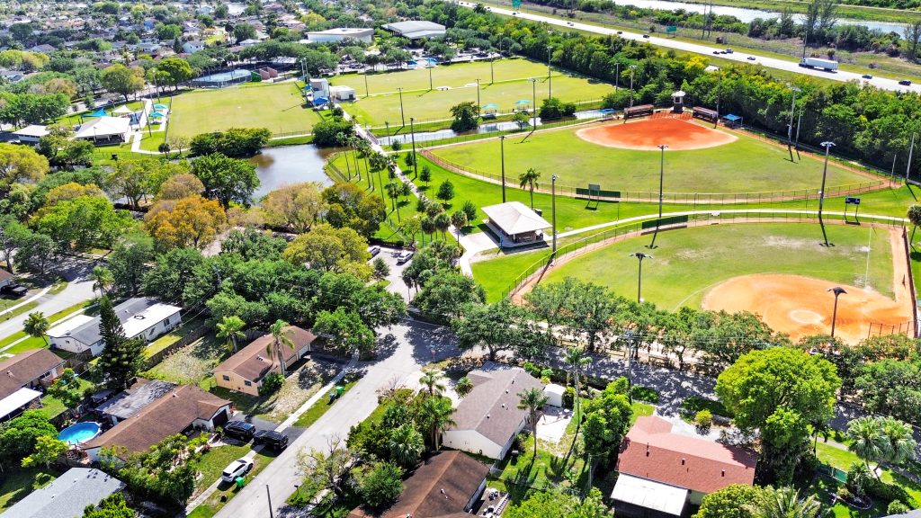 Aerial view of a community park featuring baseball fields, walking paths, and surrounding residentia.