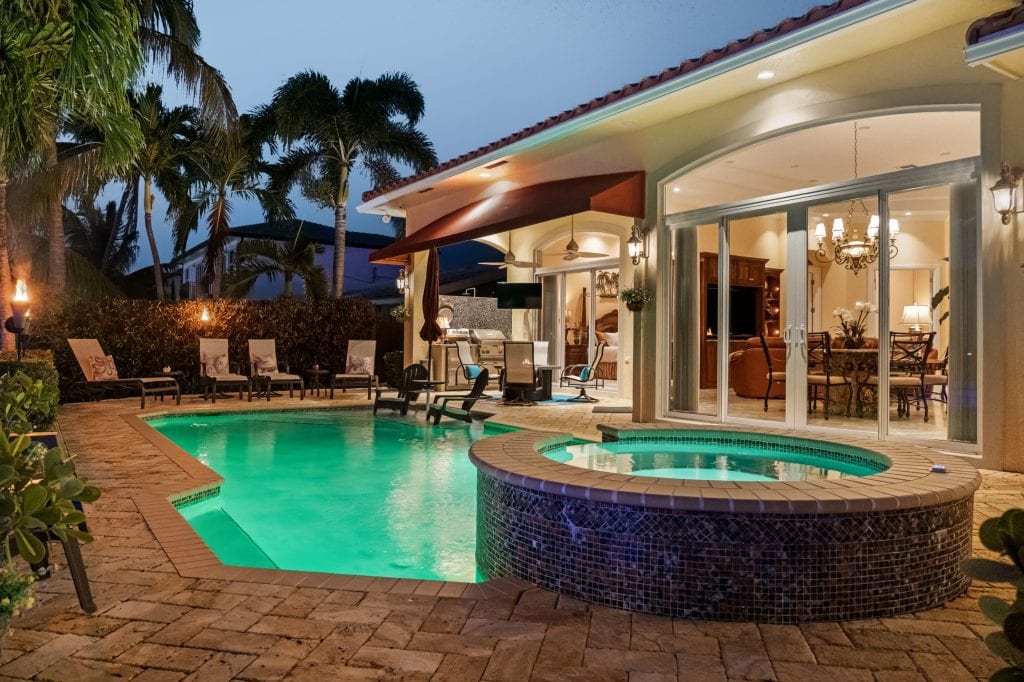 Elegant backyard pool with hot tub, outdoor lounge, and tropical landscaping.