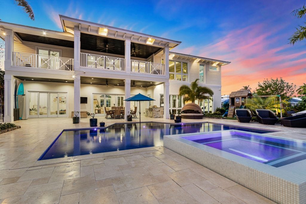 Modern luxury waterfront villa with pool, outdoor lounge, and sunset view.