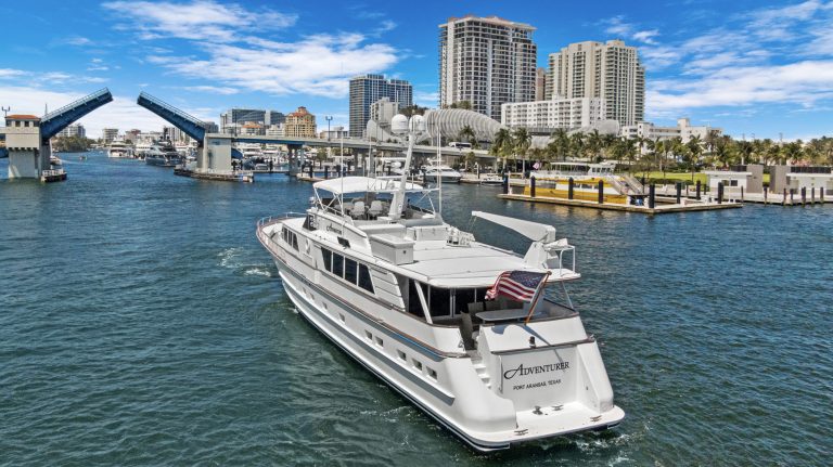 Luxury yacht cruising in San Diego harbor with city skyline in background.
