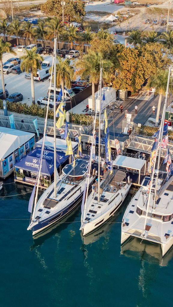 Sailboats docked at Miami marina during boat show event.