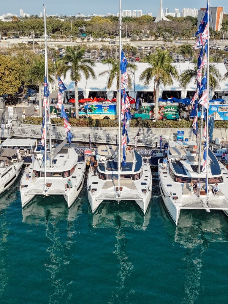 Four luxury sailboats docked at Miami marina during boat show.