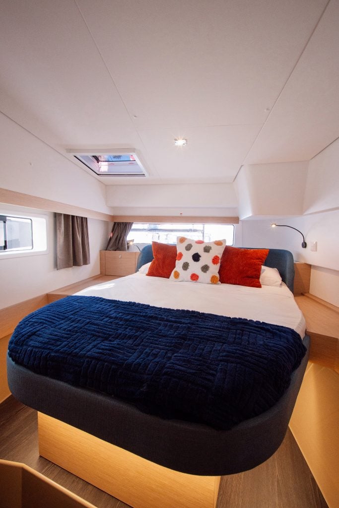 Elegant yacht bedroom with large bed, colorful pillows, and natural light.