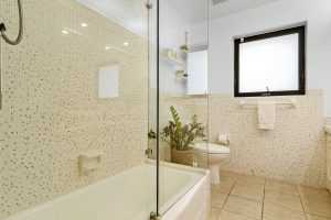 Bathroom with bathtub, shower, and natural light from window.