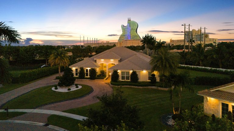 Elegant house with lush landscaping and the iconic Guitar Hotel in the background.