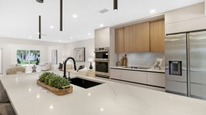Modern kitchen featuring stainless steel appliances, white countertops, and wooden cabinetry for a s.