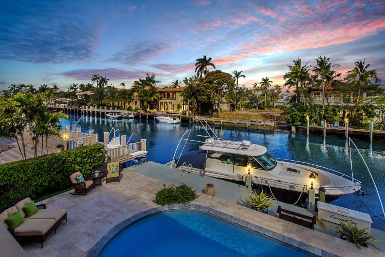 Luxury waterfront yacht dock with tropical landscape at sunset.