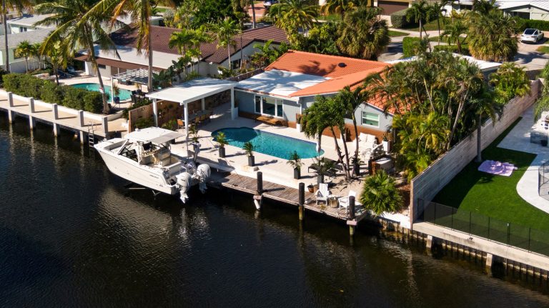 Luxury waterfront home with private dock, pool, and tropical landscaping in Florida.