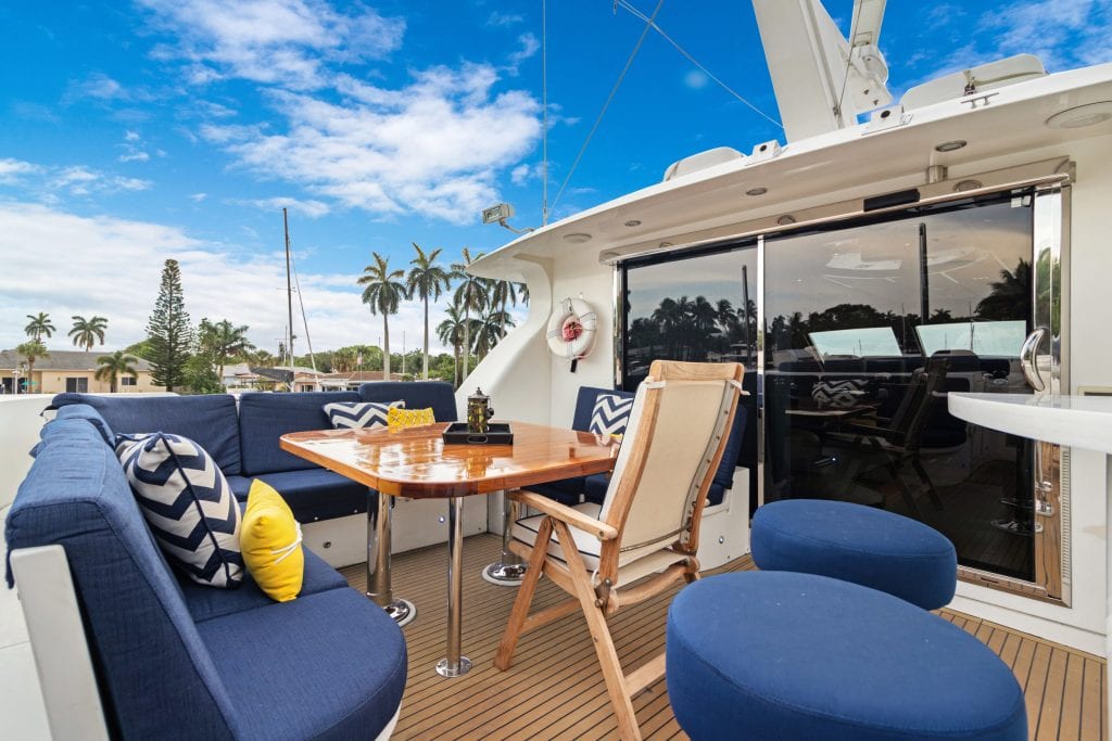 Outdoor yacht deck with comfortable seating, table, and scenic ocean views under a blue sky.