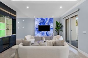 Wall-mounted flat-screen TV in contemporary living room with modern decor and natural light.