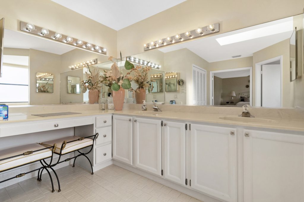 Bright bathroom with double vanity, large mirror, and decorative vases.