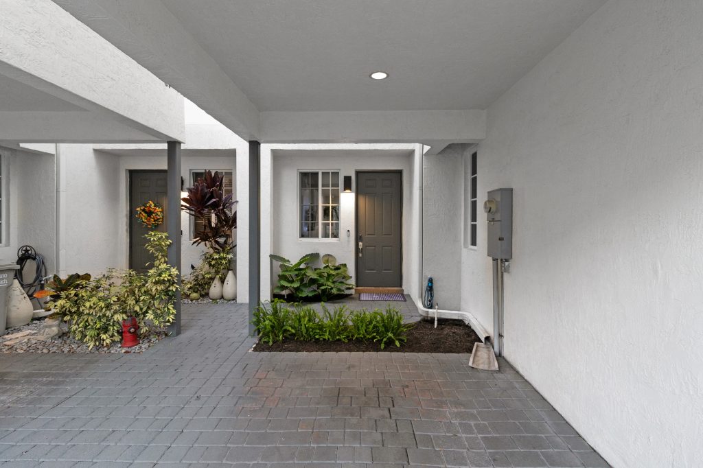 Contemporary home entrance with plants and a gray door.