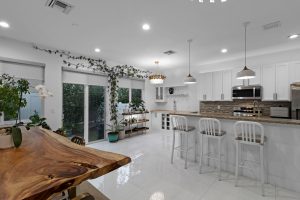 Bright modern kitchen with white cabinets, island, and large windows for natural light.