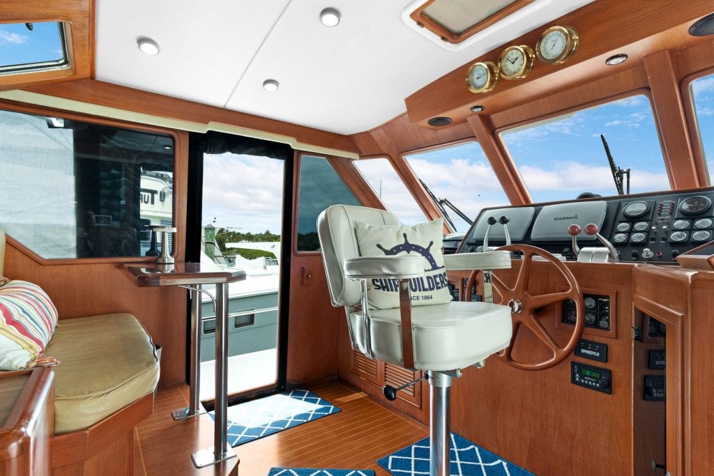 Boat helm station with steering wheel, gauges, and navigation controls.