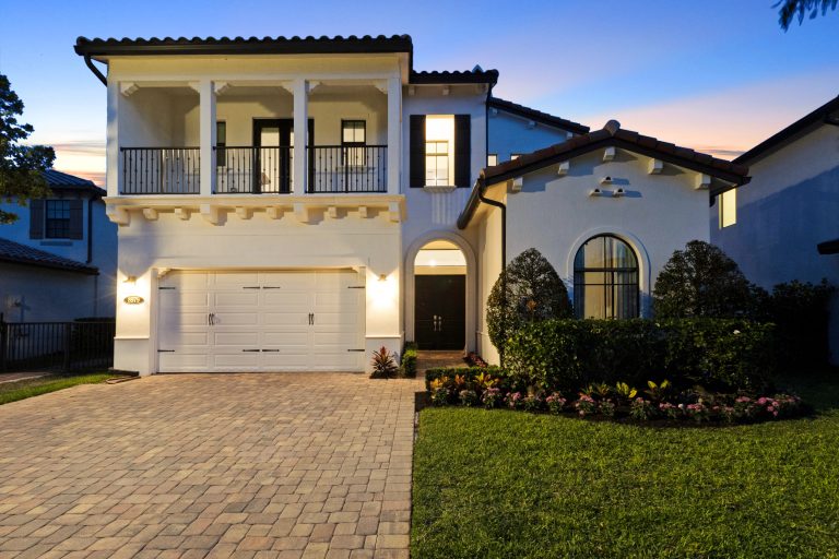 Elegant Mediterranean house with balcony, arched windows, and well-maintained garden.