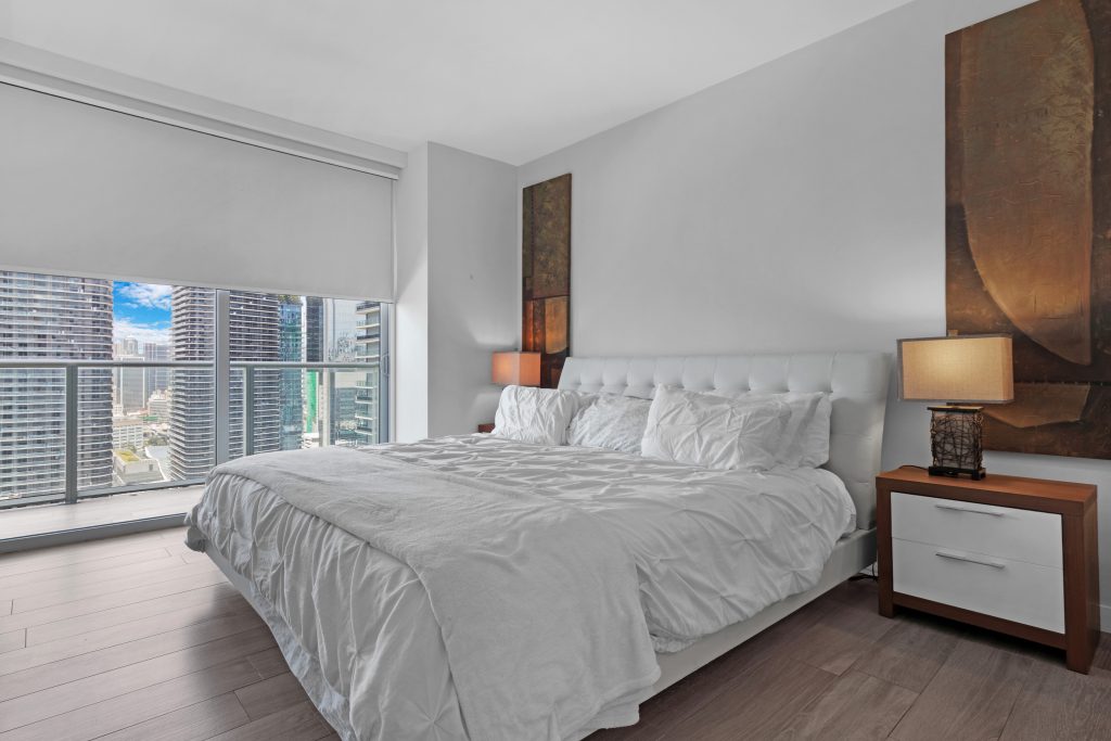 City skyline view from a modern bedroom with large window and natural light.