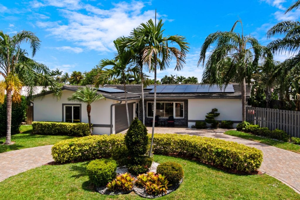 Tropical home with lush landscaping and palm trees in front yard.