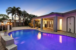 Backyard with illuminated swimming pool and outdoor living space.