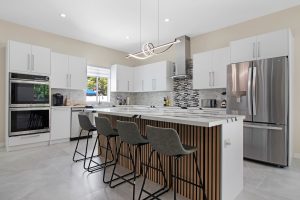 Contemporary kitchen with white cabinets, island, and stainless steel appliances.