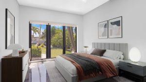 Bedroom with large window overlooking lush tropical garden and palm trees.