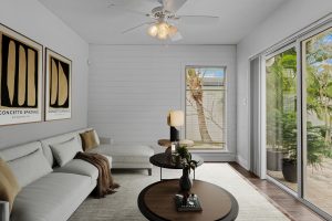 Bright living room with large windows showcasing tropical outdoor scenery and modern decor.