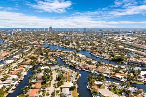 Aerial view of Miami waterfront homes featuring scenic canals and the city skyline in the background.