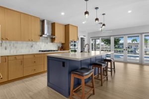 Bright, open-concept kitchen featuring a central island, wooden cabinets, and expansive windows over.