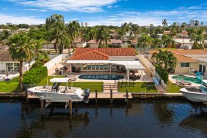 Waterfront home with boat dock, pool, and lush landscaping in Florida.