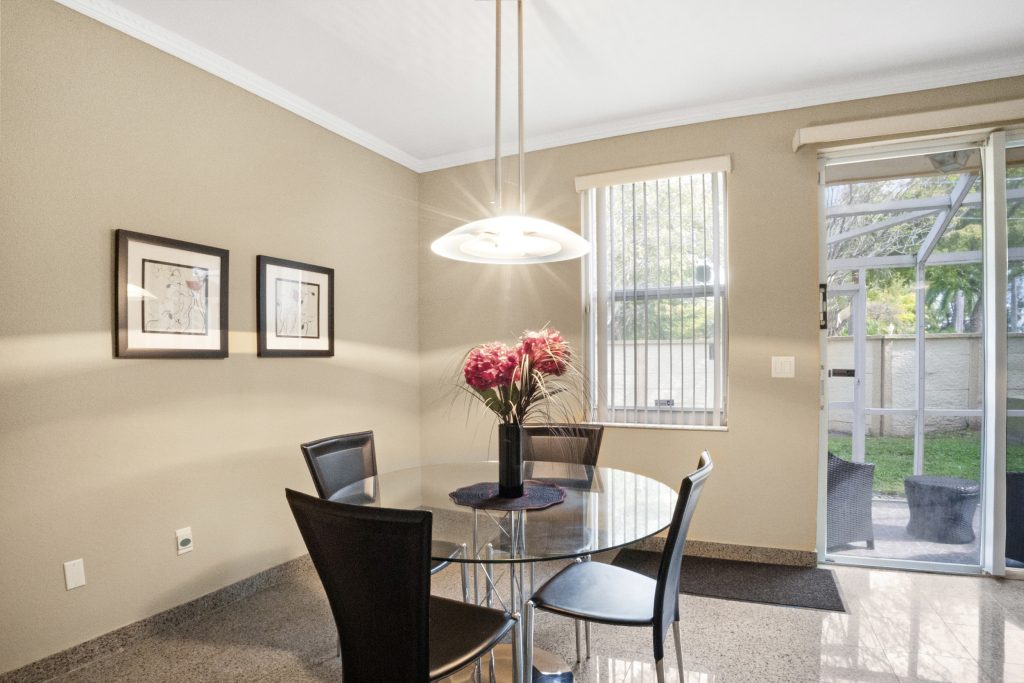 Bright dining room with glass table, black chairs, and large windows.