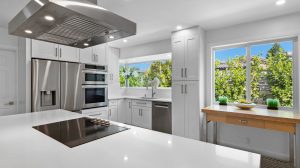 Bright, contemporary kitchen featuring stainless steel appliances and large windows with lush greene.