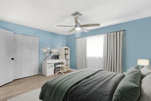 Comfortable bedroom featuring soft blue walls, large window with curtains, and modern furniture.