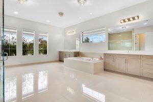 Bathroom with bathtub, vanity, and large windows for bright, airy space.