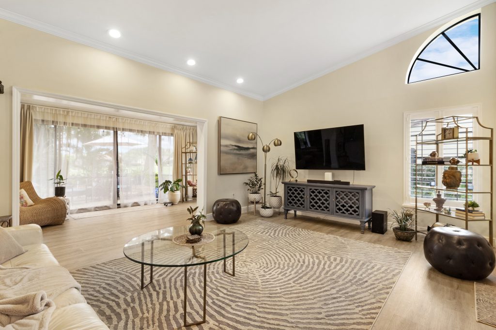 Bright living room with large windows, TV, and stylish furniture.