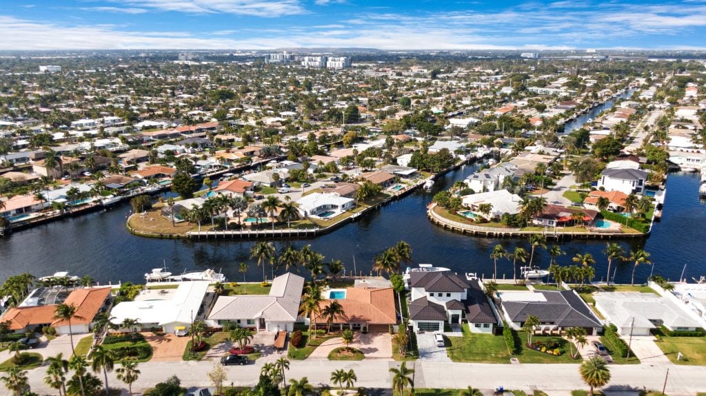Drone aerial shot of waterfront residential neighborhoods with canals and lush greenery.