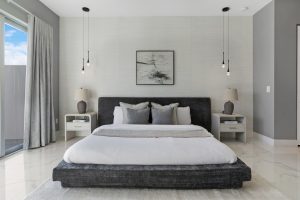 Modern bedroom with minimalist decor, neutral tones, and natural light from large window.
