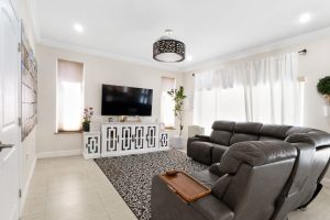 Spacious living room with black leather sofas and a large flat-screen TV.