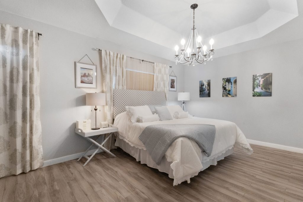 Bright bedroom with chandelier, artwork, and cozy bedding.