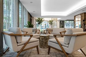 Elegant hotel lobby with beige armchairs and large windows.