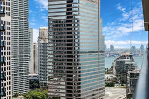 View of tall modern skyscrapers in a city with a river in the background.