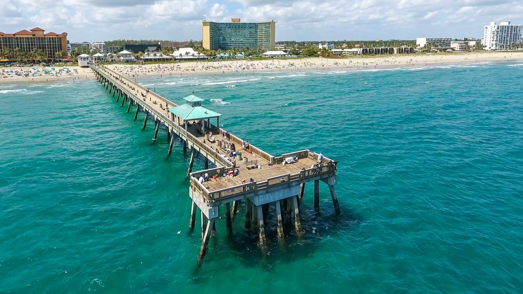 Pier extending into the Atlantic Ocean with clear blue waters and sandy shoreline.