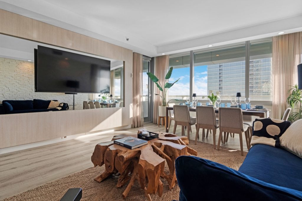 Spacious living room with large windows and cityscape view, stylish furniture, and natural light.