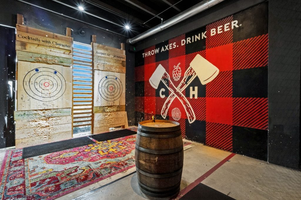 Indoor axe throwing area with beer-themed decor and targets for recreational fun.